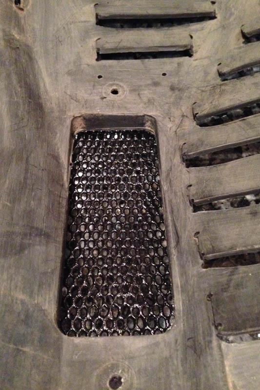 The fender liner originally located an air duct for cooling the brakes &mdash; I removed the duct to make way for the cooler. The duct opening is covered with aluminum mesh to keep rocks from striking the oil cooler. The mesh is painted with a stone guard coating (like what's used on rocker panels).